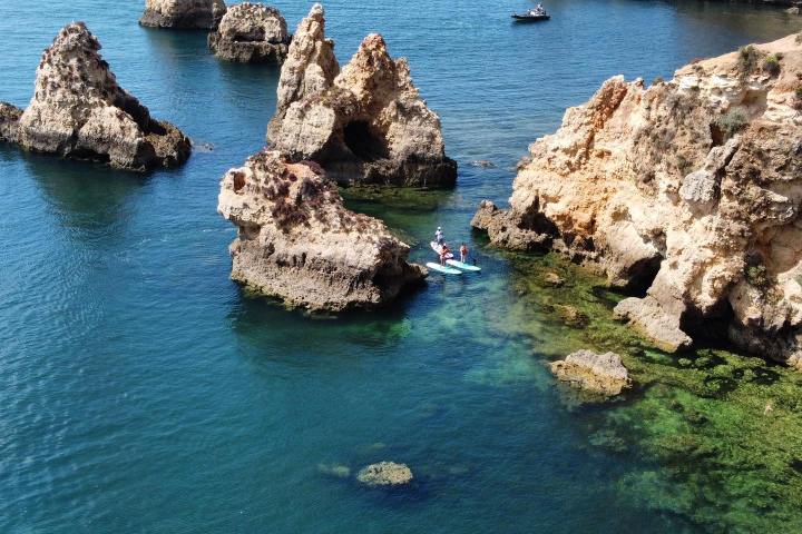 Kayakers explore rocky sea cliffs and turquoise water.