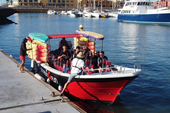 A small tour boat with passengers docked at a marina.