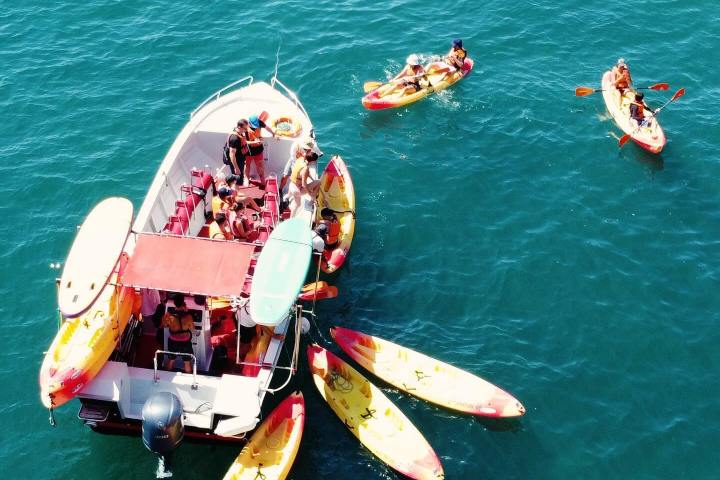 Boat with people and kayaks on a blue ocean.
